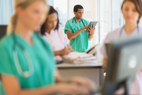 Doctors and nurses working at desks in hospital.