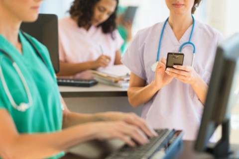 Doctors and nurses working at desks in hospital.