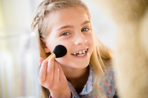 Girl (8-9) applying make-up