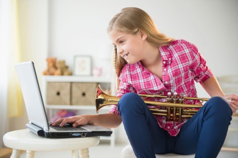 Girl (8-9) with trumpet using laptop