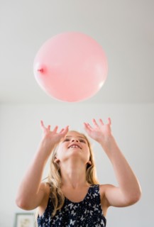 Girl (8-9) playing with pink balloon