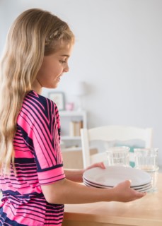 Side view of girl (8-9) holding plates