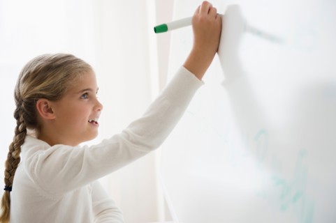 Portrait of girl (8-9) writing on white board