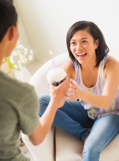 Young man giving cupcake with candle to woman