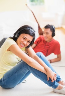 Young woman and man listening music with headphones on