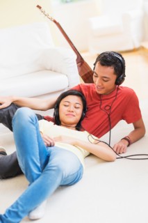 Young woman and man listening music with headphones on