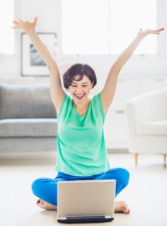 Young woman cheering in front of laptop