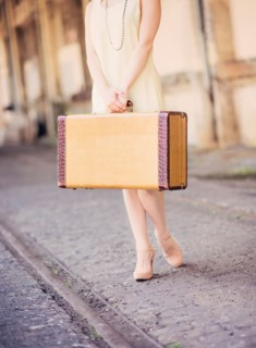 Low section of woman in dress holding suitcase at train station