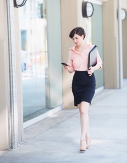 Portrait of business woman walking and text messaging