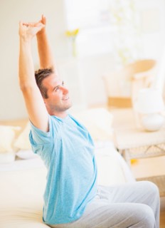 Man sitting on bed and stretching