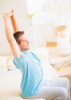 Man sitting on bed and stretching