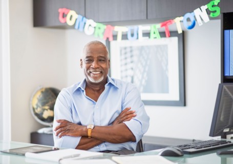 Portrait of man in office, congratulations sign behind