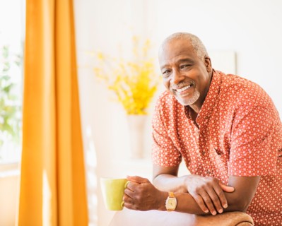 Portrait of men leaning on armchair, holding mug