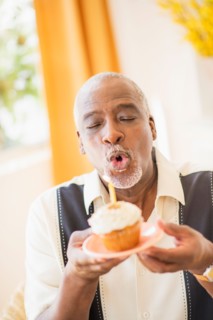 Portrait of man holding cupcake and blowing out candle