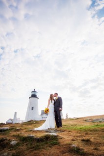Portrait of married couple kissing, lighthouse in background