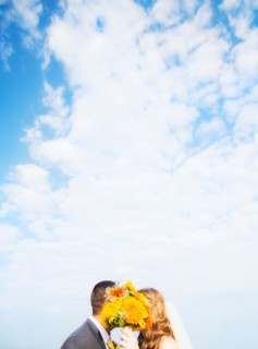 Portrait of married couple kissing behind bouquet