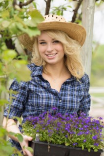 Portrait of young woman holding potted flowers