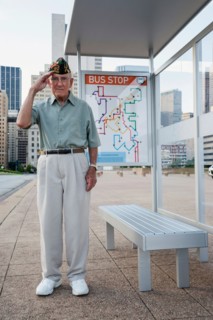 Senior man standing and saluting at bus stop