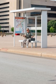Senior man sitting at bus stop with fishing rod