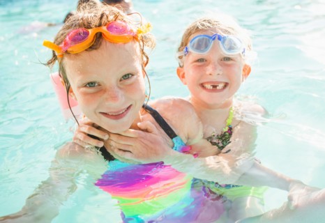 Girlfriends (4-5, 8-9) playing in swimming pool