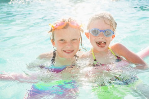 Girlfriends (4-5, 8-9) playing in swimming pool
