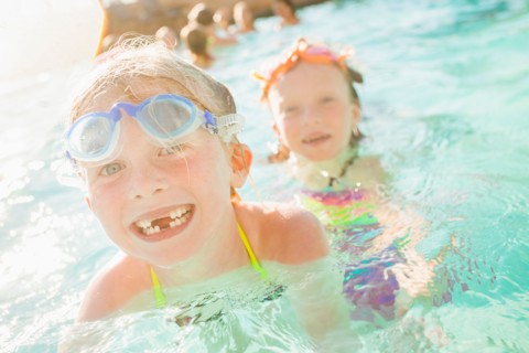 Girlfriends (4-5, 8-9) playing in swimming pool