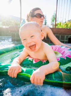 Baby boy (18-23 months) playing in swimming pool with his mother
