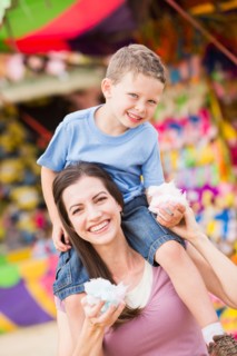 Happy mother with son (4-5) in amusement park eating cotton candy