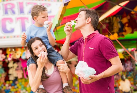 Happy family with son (4-5) in amusement park eating cotton candy