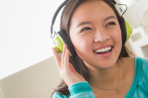 Girl (16-17) listening to music wearing headphones
