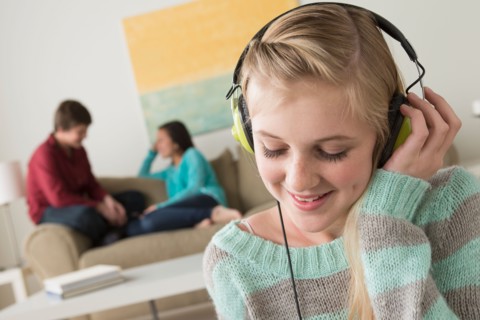 Girl (14-15) listening to music wearing headphones