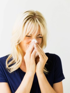 Studio portrait of blonde woman blowing nose