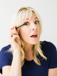 Studio portrait of blonde woman applying mascara
