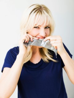 Studio portrait of blonde woman ripping tape