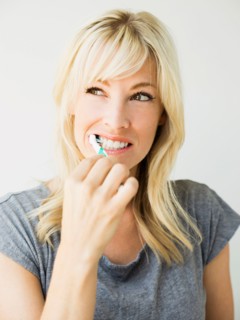 Studio portrait of blonde woman cleaning teeth