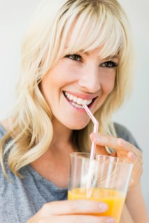 Studio portrait of blonde woman drinking orange juice