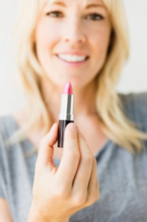 Studio portrait of blonde woman holding pink lipstick