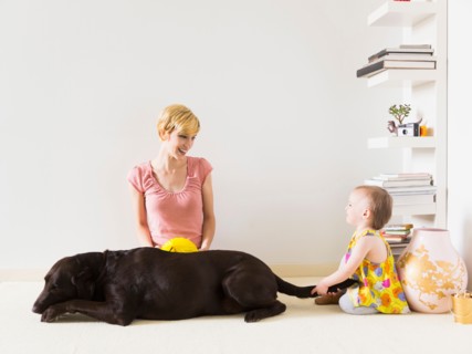 Mother with baby daughter (12-17 months) playing with dog
