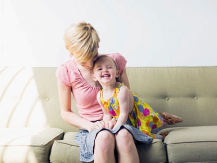 Mother with daughter (12-17 months) sitting on sofa