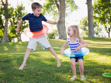 Two kids (4-5, 6-7) playing with inflatable rings in park
