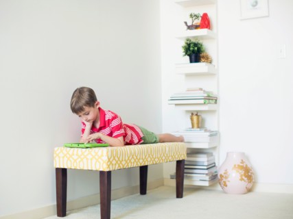 Boy (6-7) lying on bench using digital tablet