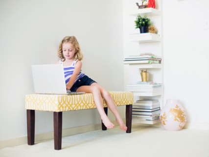 Girl (4-5) sitting on bench using laptop