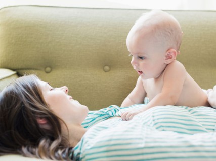 Mother and baby boy (6-11 months) lying on sofa