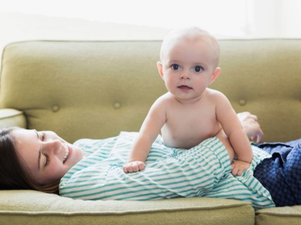 Mother and baby boy (6-11 months) lying on sofa