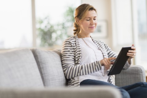 Woman sitting on sofa using tablet pc.