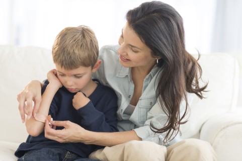 Mother helping son (6-7) put on bandaid.