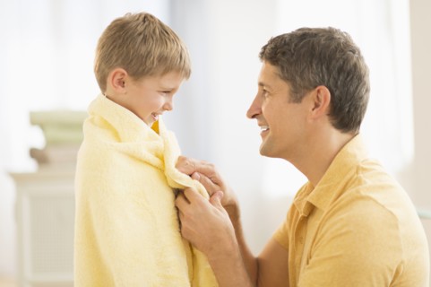 Father with son (6-7) wrapped in towel.