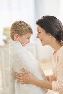 Mother with son (6-7) wrapped in towel.