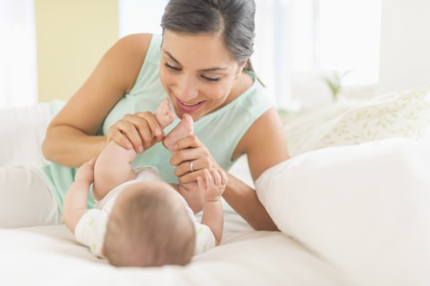 Mother and baby (2-5 months) lying on bed.