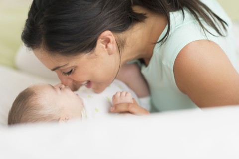 Mother and baby (2-5 months) lying on bed.